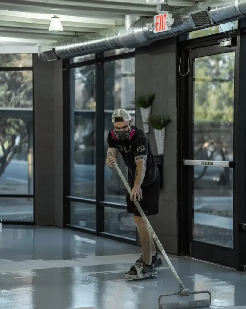 Professional installer rolling out an epoxy coating across a commercial concrete floor